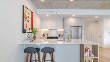 A modern kitchen with white cabinetry, a stainless steel refrigerator, and a central island with bar stools.