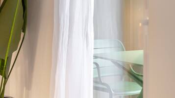 A room with a potted plant, a glass table, and a chair.