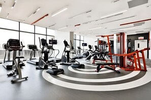 A modern gym with treadmills, elliptical machines, and weightlifting equipment. - Chic 1BR apartment in DT MTL (Montréal)
