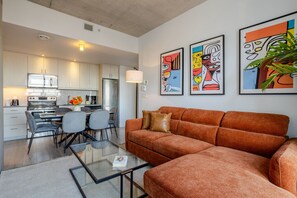 Un salon moderne avec un canapé, une table basse en verre et un coin repas comprenant des chaises et une table.