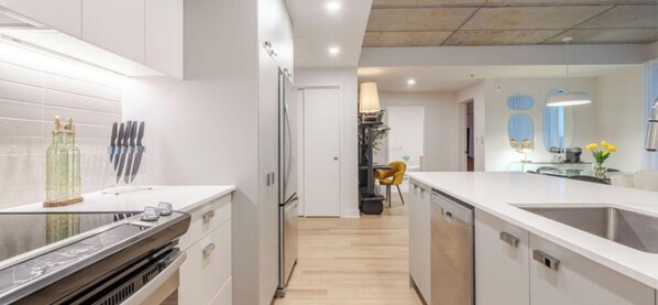 A modern kitchen with white cabinetry, stainless steel appliances, and a wooden floor. - Old Montreal Haven – Bright, Spacious & Walkable (Montreal)