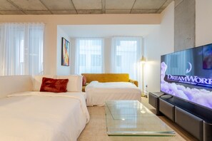 Ein Hotelzimmer mit zwei Betten, einem Fernseher und einem großen Fenster.