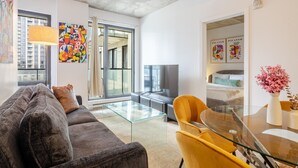 Una sala de estar moderna con un sofá, una mesa de centro de vidrio y una silla amarilla.
