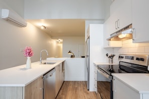 A modern kitchen with white cabinetry, a built-in oven, and a dishwasher. - MTL Trendy Hideaway in Rosemont (Montreal)
