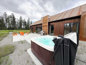 Eine Holzhütte mit Whirlpool, Sitzgelegenheit im Freien und Blick auf den Wald.