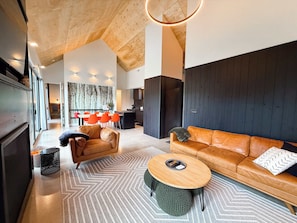 Ein modernes Wohnzimmer mit Sofa, Couchtisch und einem Essbereich mit Stühlen.