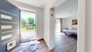 Een moderne slaapkamer met een bed, een deur naar een balkon en uitzicht op een tuin.