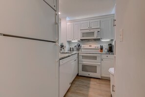 Eine kleine Küche mit weißen Schränken, einer Mikrowelle, einem Backofen und einem Toaster.