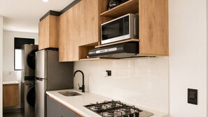 A modern kitchen with a built-in gas stove, stainless steel appliances, and wooden cabinetry. - Apartaestudio Luxury (Sabaneta)