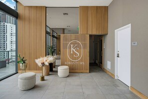 Un intérieur de spa moderne avec un comptoir d’accueil, des panneaux de bois et une vue sur le paysage urbain.