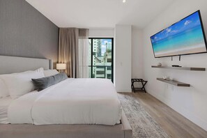 Habitación de hotel moderna con una cama grande, un televisor de pantalla plana, un balcón con vistas a la ciudad y una decoración minimalista.