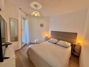 Un dormitorio con una cama grande, lámparas de noche, un espejo y un ventilador de techo.