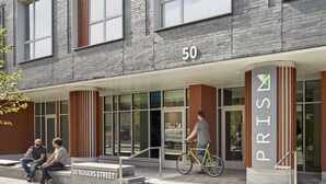 Een gebouw met een modern ontwerp, met een fietsenstalling en een bord met het nummer 50.