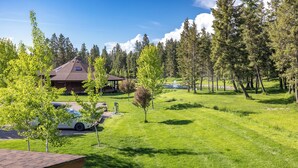 A lodge with a large roof, a covered patio, and a pond. - Strawberry Moon in Whitefish with Hot Tub (Whitefish)