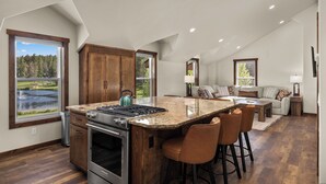 A kitchen with a large island, wooden cabinets, and a view of a lake. - Strawberry Moon in Whitefish with Hot Tub (Whitefish)