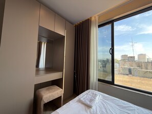A hotel room with a bed, a bench, a wardrobe, and a large window with a city view. - 408s Tara-jre Jabal Al Lweibdeh With Stunning View (Amman)