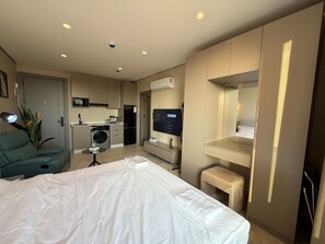 A modern hotel room with a bed, a desk, a chair, a small kitchenette, and a TV. - 408s Tara-jre Jabal Al Lweibdeh With Stunning View (Amman)