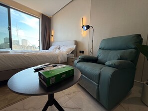 A hotel room with a bed, a green armchair, a small table with a box, and a window with a city view. - 408s Tara-jre Jabal Al Lweibdeh With Stunning View (Amman)