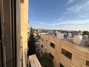 A view from a window overlooking a cityscape with buildings, a clear sky, and water tanks on a rooftop. - 408s Tara-jre Jabal Al Lweibdeh With Stunning View (Amman)