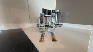 Un comptoir de cuisine avec deux bouteilles d’eau étiquetées « JRE » et deux paquets de collations.