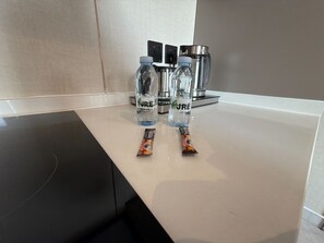 Eine Küchenarbeitsplatte mit zwei Wasserflaschen mit dem Aufdruck 'JRE' und zwei Tüten mit Snacks.