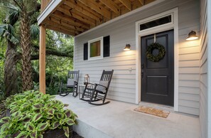 A porch with two rocking chairs, a door with a wreath, and a small table with a lantern. - Serene 3-bedroom house with AC in charming St. Augustine (St. Augustine)