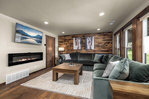 Ein Wohnzimmer mit Kamin, einer Eckcouch, einem Couchtisch und Kunstwerken an den Wänden.