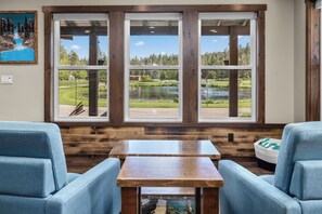 Ein Zimmer mit einem großen Fenster, einem Holztisch und zwei blauen Stühlen.