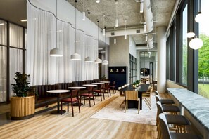 Ein modernes Restaurant mit runden Tischen, Bänken und hängenden Pendelleuchten.