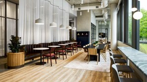 En moderne restaurant med runde borde, bænke og hængende pendellamper.