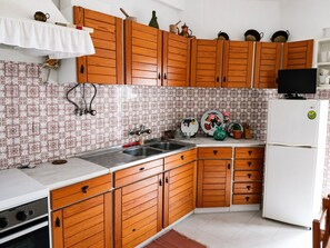 Eine Küche mit Holzschränken, einer Edelstahl-Spüle und einem weißen Kühlschrank.
