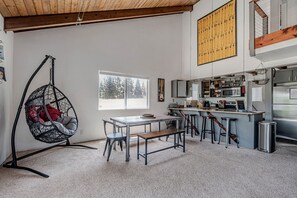 Una cocina moderna con comedor, que incluye un sillón colgante, una mesa con bancos y un ventanal grande.
