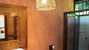Ein Badezimmer mit Holzwaschtisch, einer weißen Spüle, Toilette, Spiegel und Duschbereich.
