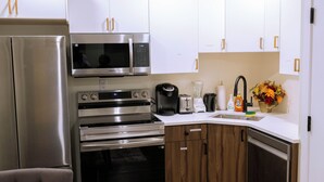 Een moderne keuken met roestvrijstalen apparatuur, een inbouwoven, magnetron en koffiezetapparaat.
