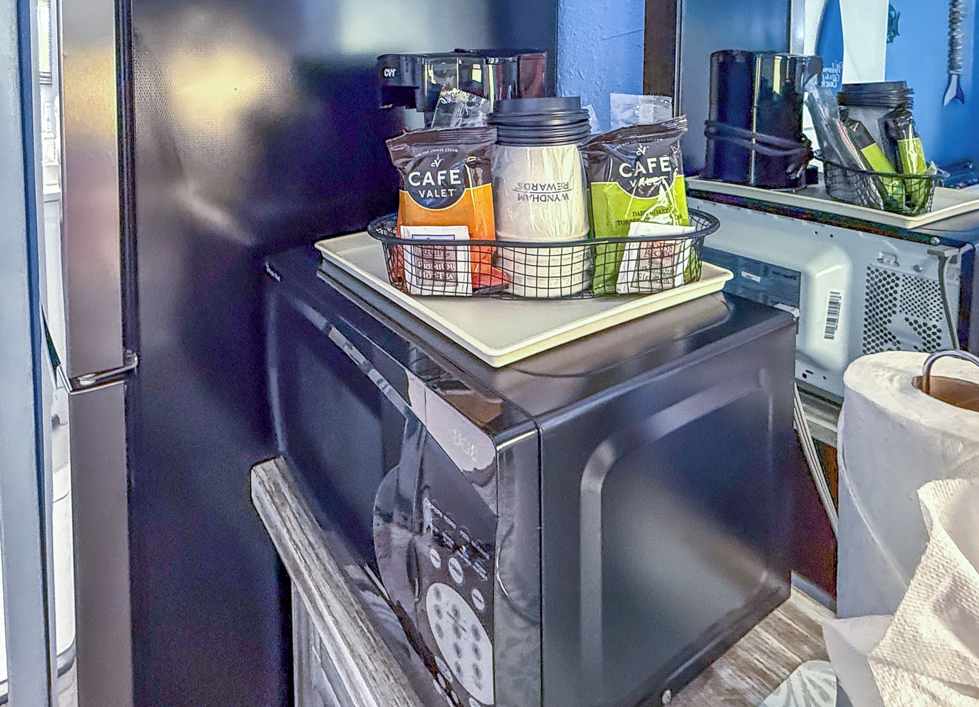 Una kitchenette con cafetera, máquina de café y soporte para cápsulas de café.