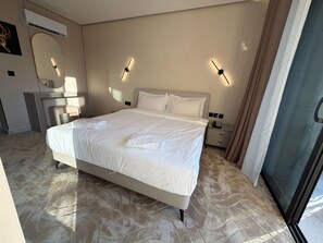 A hotel room with a large bed, a bedside table, a mirror, and a wall-mounted air conditioner. - 409 Tara-jre Jabal Al Lweibdeh With Stunning View (Amman)