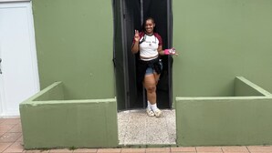 Uma pessoa em pé numa porta, com um gato deitado no chão.