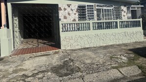 Edifício com fachada de pedra, portão de metal e varanda com grades.