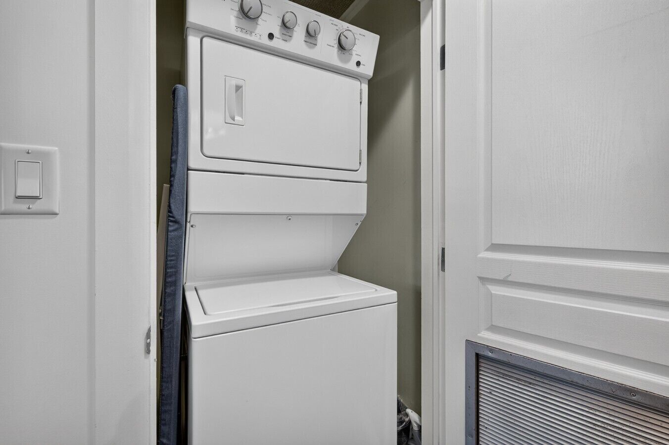 A white wall-mounted washer and dryer unit with control knobs and a door.