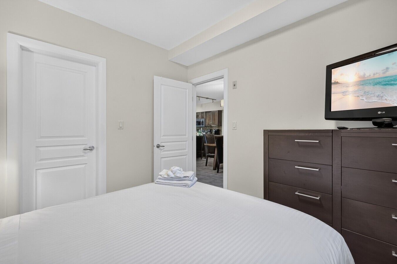 A hotel room with a bed, a TV, and a dresser.