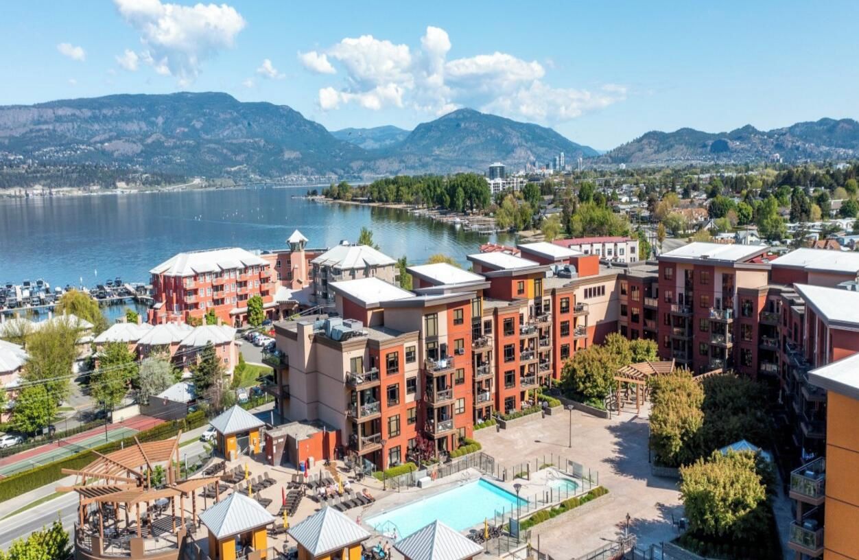 A hotel with multiple floors, a swimming pool, and a view of a lake and mountains.