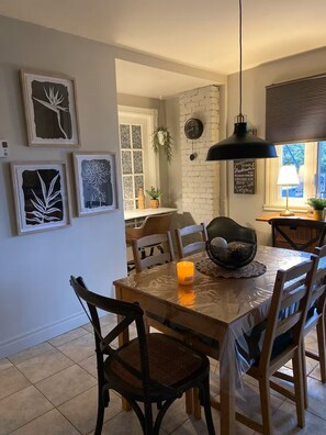 A dining area with a wooden table, chairs, a candle, and wall art. - Warm little jewels! (Longueuil)