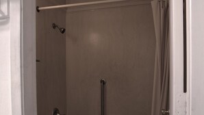 Ein Badezimmer mit Toilette, Badewanne, Duschvorhang und Haltestange.