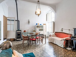 Ein gemütliches Zimmer mit Esstisch, Stühlen, einer Couch, einer Lampe und einem Fernseher.