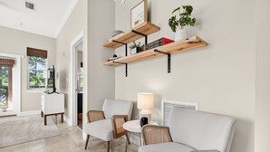 En moderne stue med en sofa, to lænestole, et lille bord og en lampe. Træhylder med bøger og en plante.