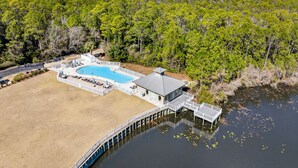 Oversigtsbillede af en ejendom ved en sø med swimmingpool, badebro og skov.