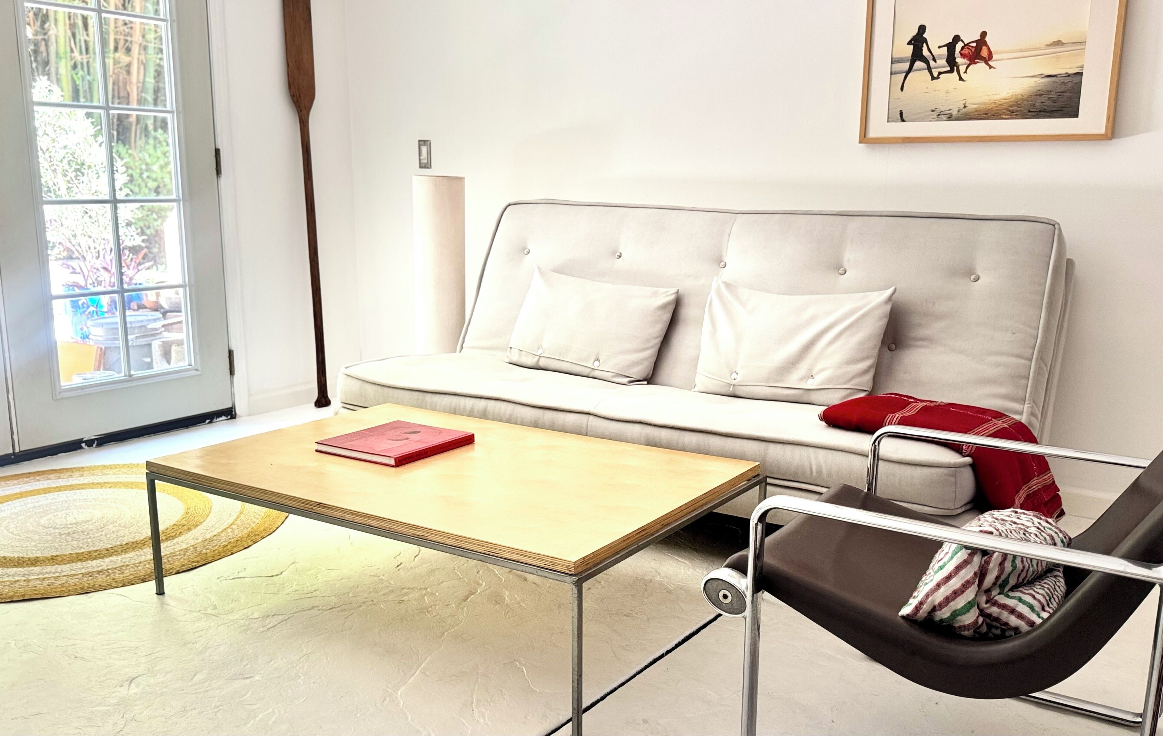 Un salon moderne avec un canapé, une table basse, un fauteuil et une fenêtre.