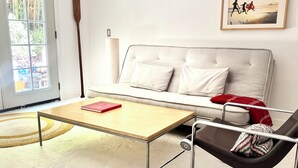 A modern living room with a sofa, a coffee table, a chair, and a window. - Fantastic studio with AC in vibrant Los Angeles neighborhood. (Los Angeles)