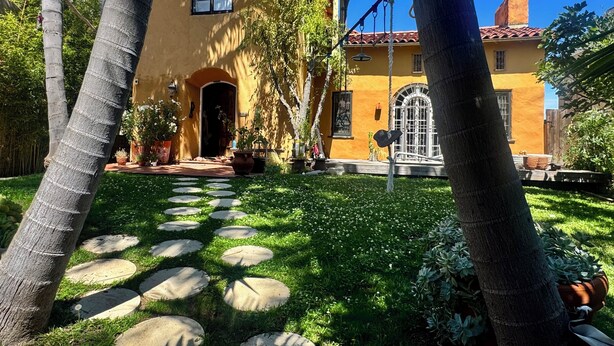 A yellow building with a red-tiled roof, a circular window, and a door. - Fantastic studio with AC in vibrant Los Angeles neighborhood. (Los Angeles)