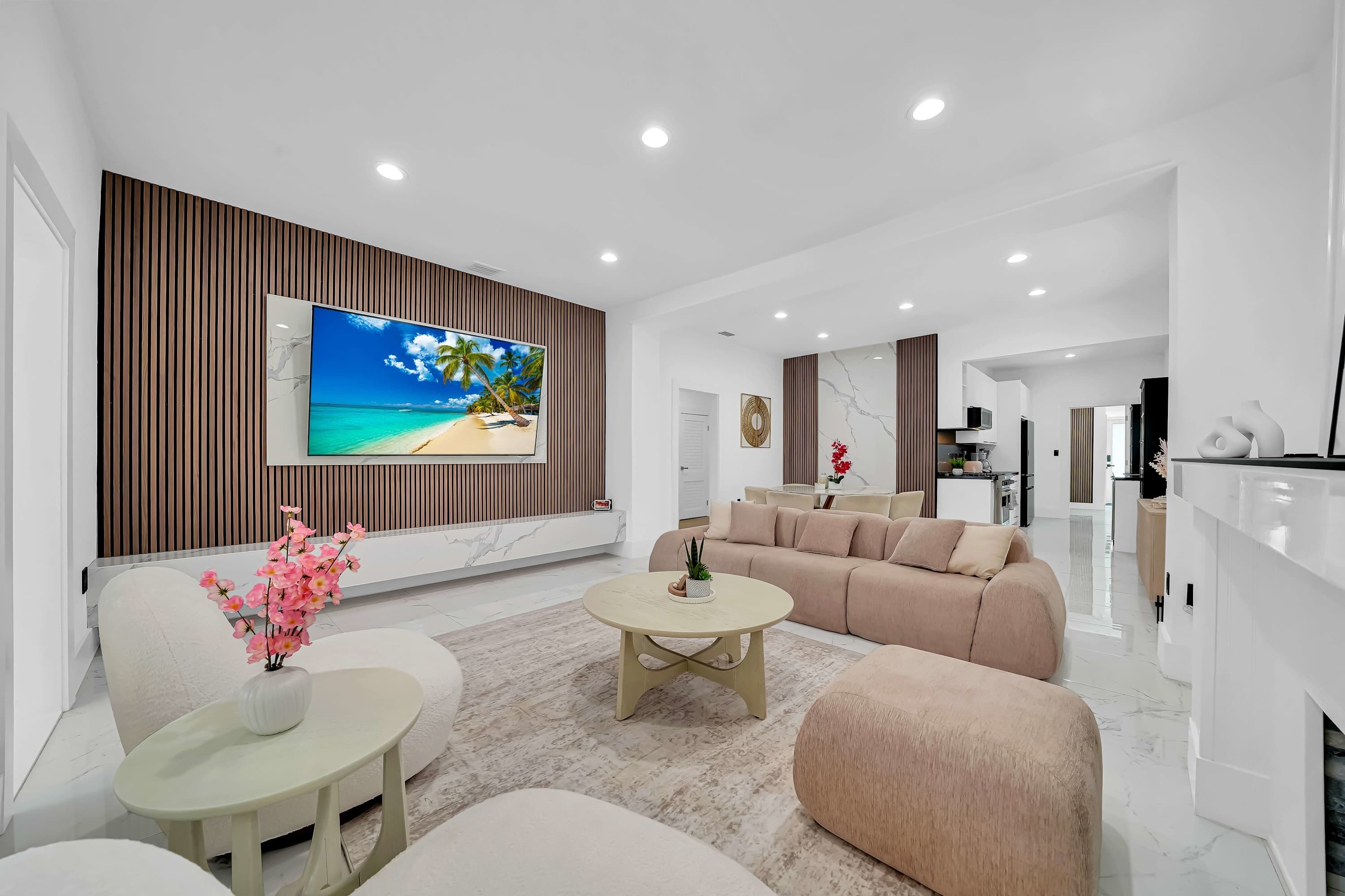 A modern living room with a large flat-screen TV, a beige sofa, a coffee table, and a decorative vase.